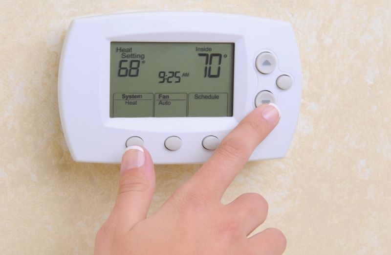 woman turning down the heat on thermostat