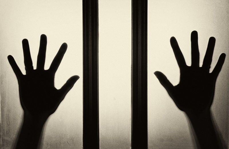 Two hands of a trapped person pressed against glass