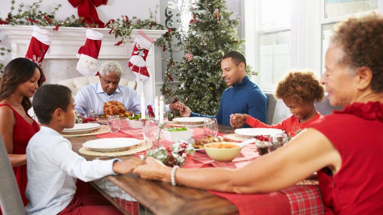 A family at the dinner table saying short christmas prayers