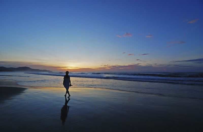 Woman walking down the beach. Photo by es_sooyon, Thinkstock.