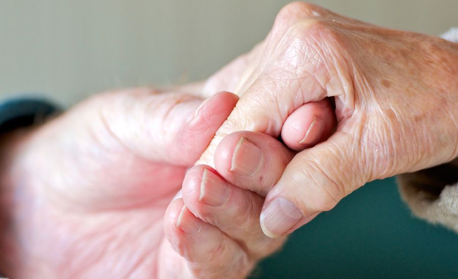 A closeup of two seniors holding hands