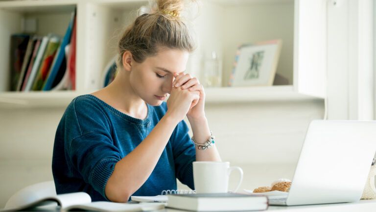 Woman praying at her desk as a thing to do during lent