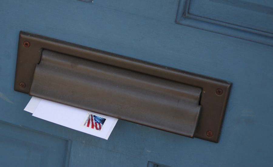 A mail slot with a returned letter in it