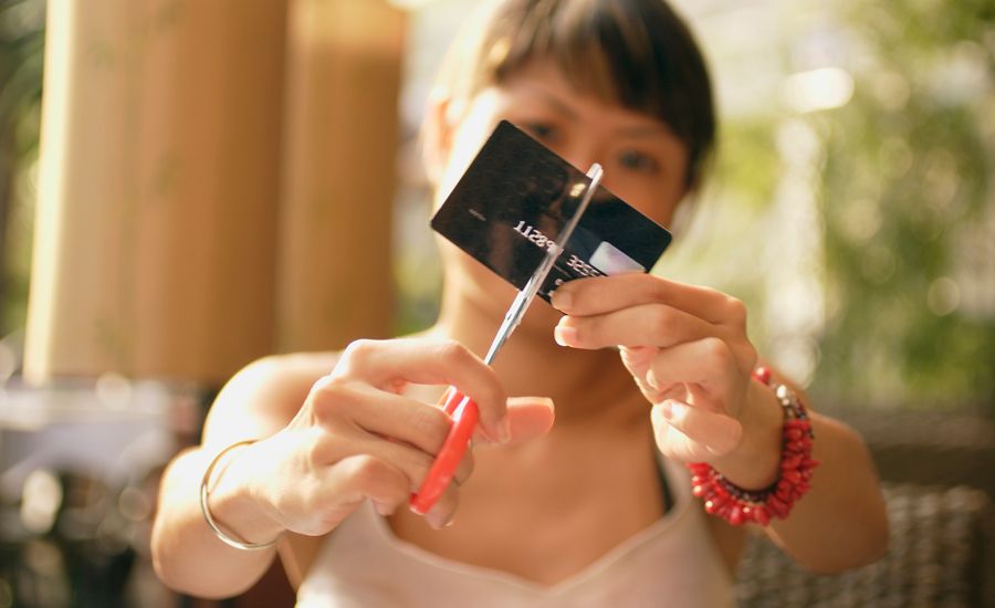 A woman cuts her credit card in half.