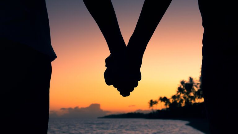 Royalty-free stock image: A couple on the beach holds hand at sunset