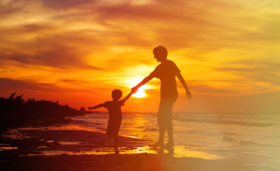 Parent and child on the beach at sunset. Photo: Thinkstock.