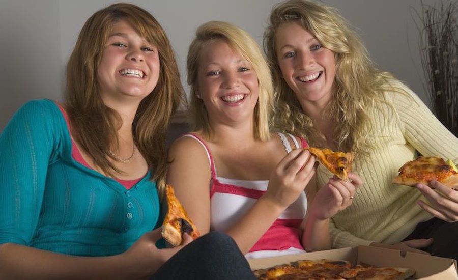 Teen girls eating pizza. Photo: 123RF(r).