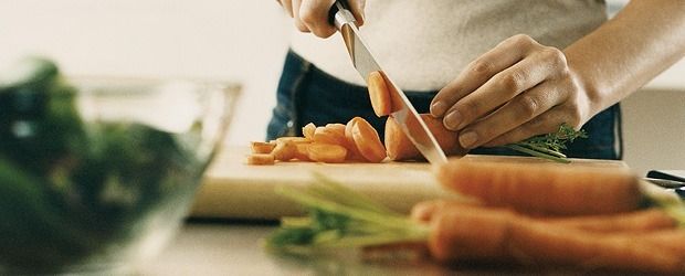 A close-up of a man's hands chopping carrots