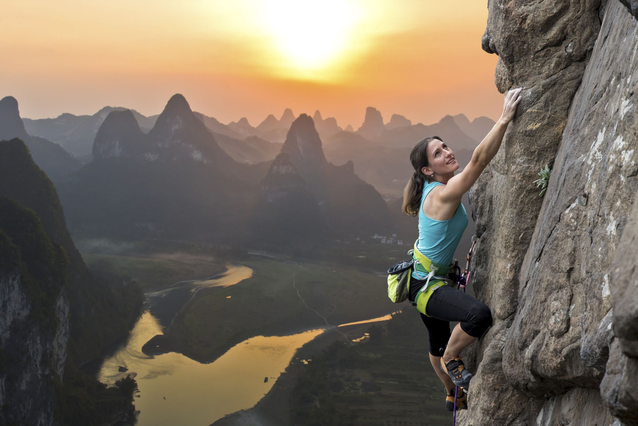 woman climbing a mountain at sunrise