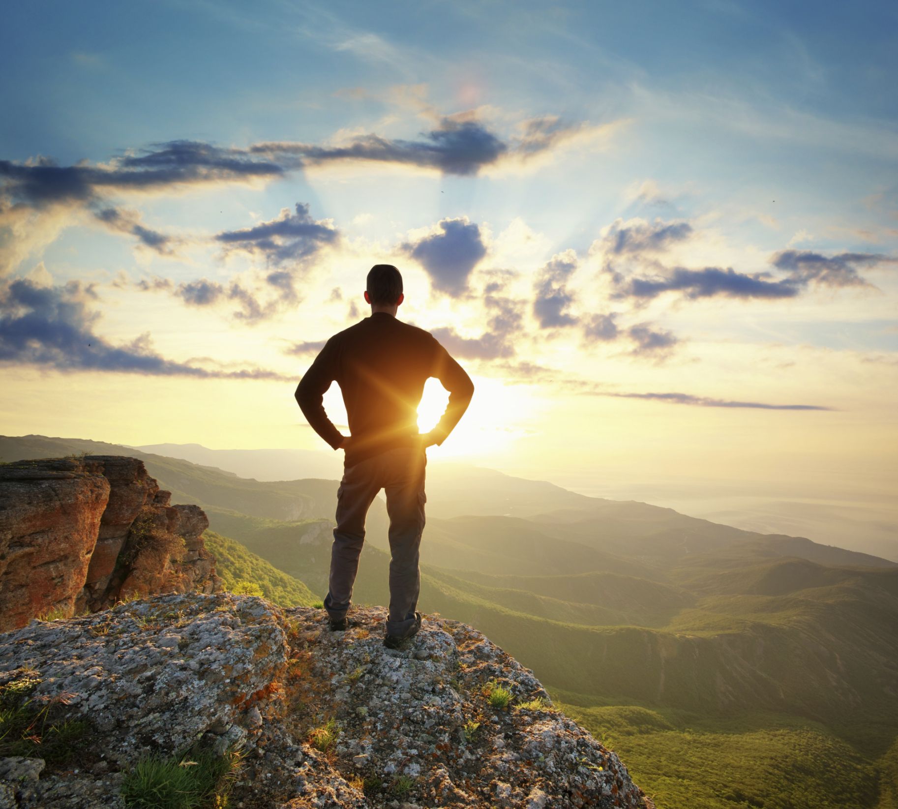 man standing on a cliff at sunrise