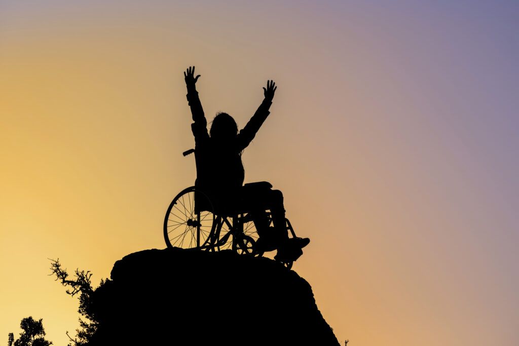 person in wheelchair at the top of a mountain at sunset