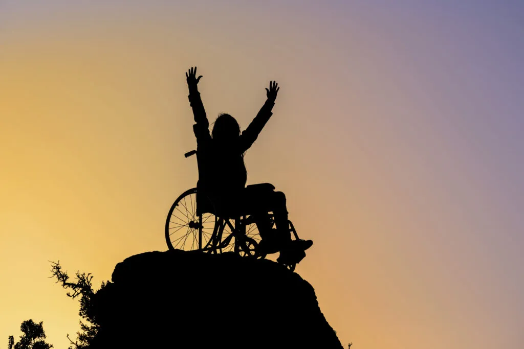 person in wheelchair at the top of a mountain at sunset