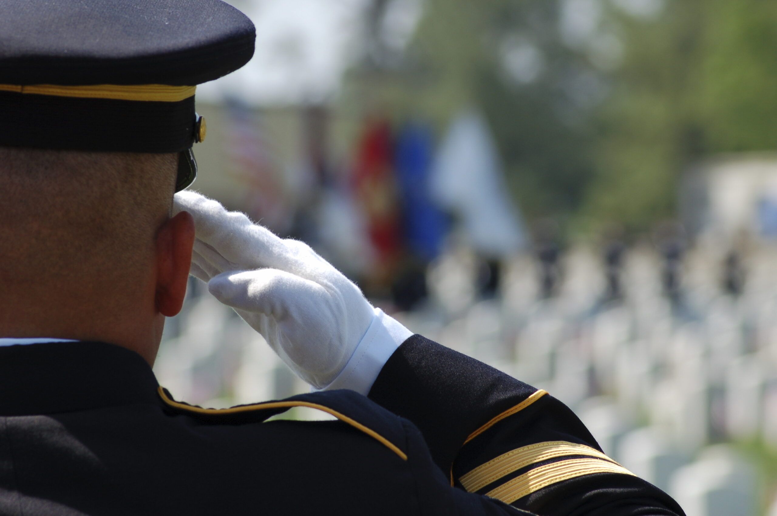Soldier saluting fallen soldiers in a cemetary on Memorial Day