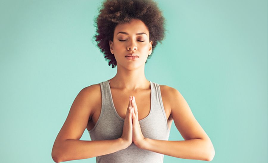 young woman sitting in a yoga pose praying hands