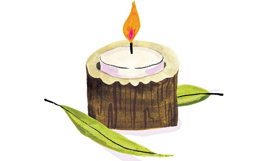 A glowing votive candle, nestled in a eucalyptus branch