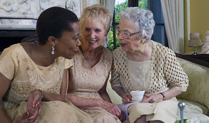 Three mature woman converse over coffee.