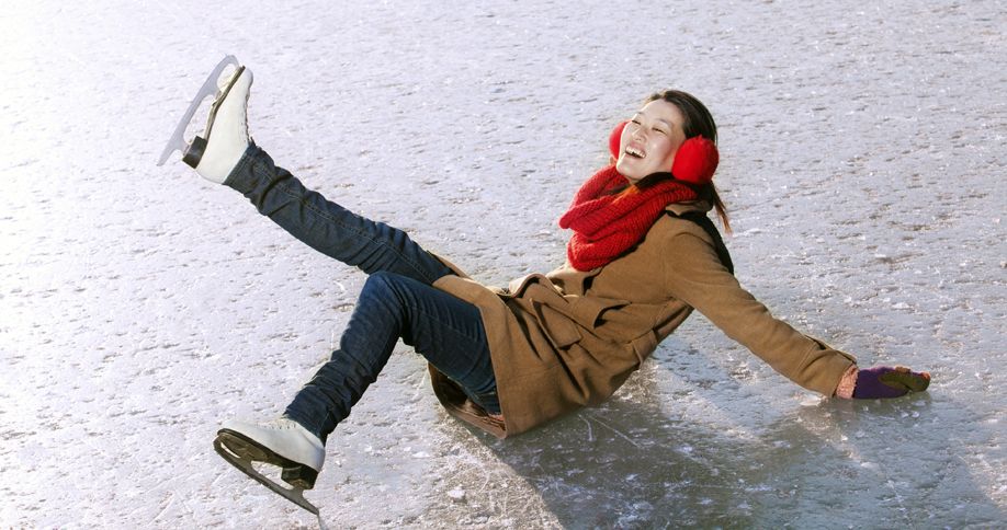 A good-natured woman takes a spill while ice skating in stride.