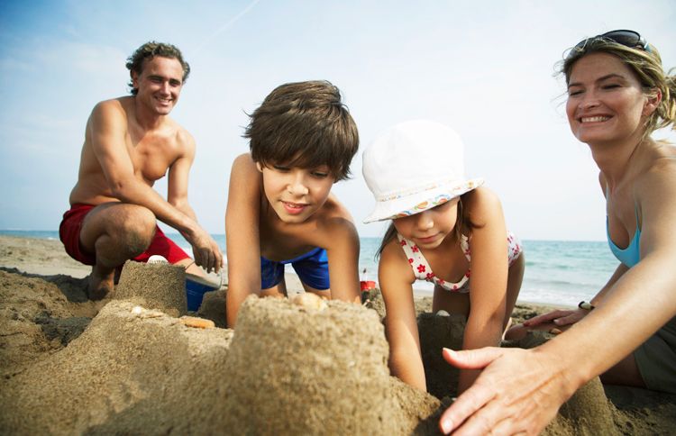 A happy family builds sand castles at the beach.