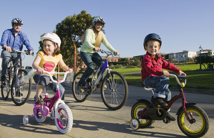 A smiling family of four takes a bike tour of their hometown.