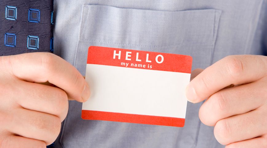 A man places a Hello My Name Is tag on his shirt pocket.