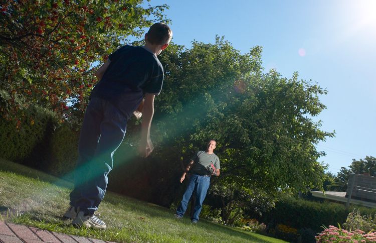 A father plays catch with his son in the back yard.