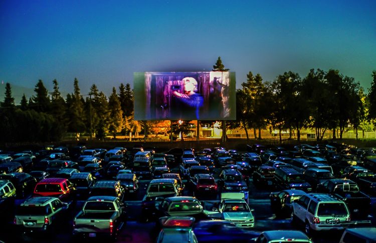 Row after row of families in cars enjoy a movie at their local drive-in.
