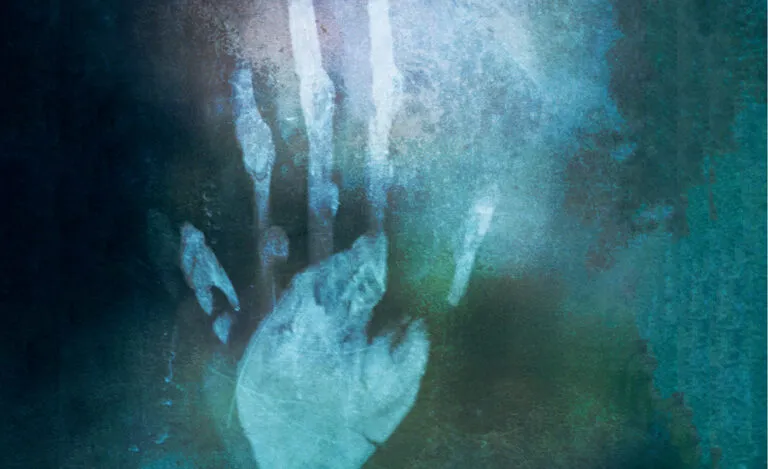 A mysterious hand appears against the green-gray of a mirror.