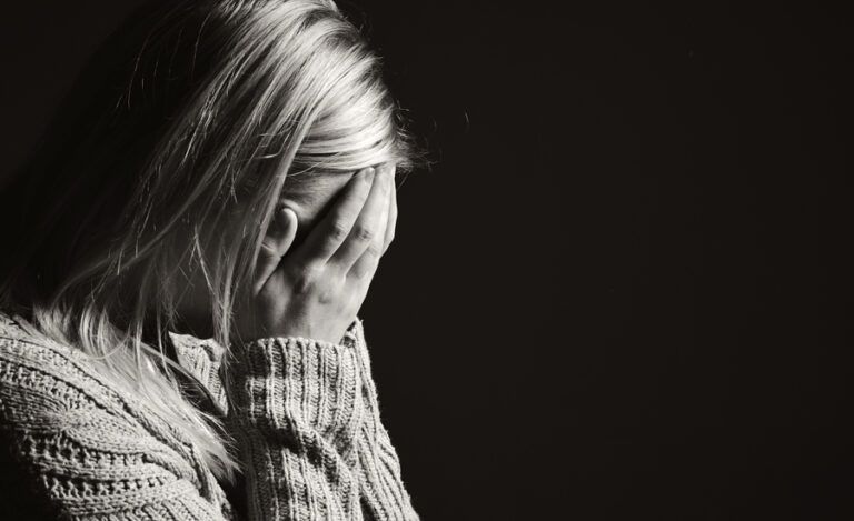 a woman holds her face in her hands in grief