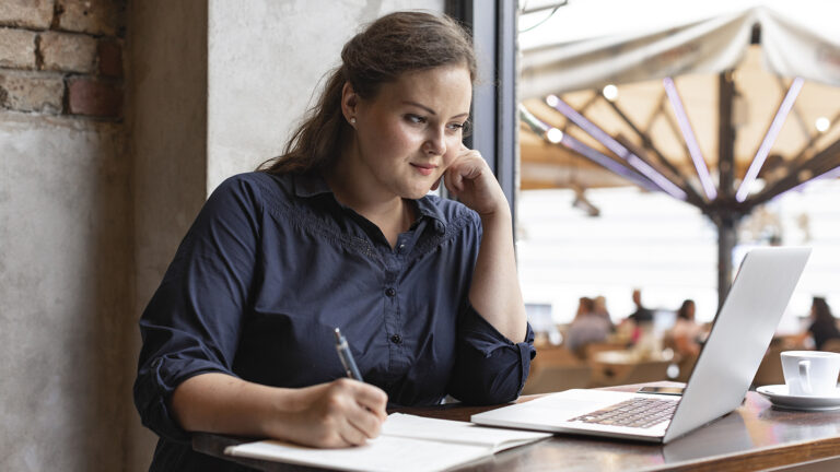 Woman at a cafe giving herself a gratitude intervention by writing down what she is grateful for