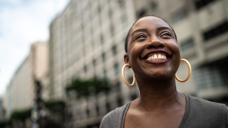 Woman looking up and smiling to learn how to be more grateful