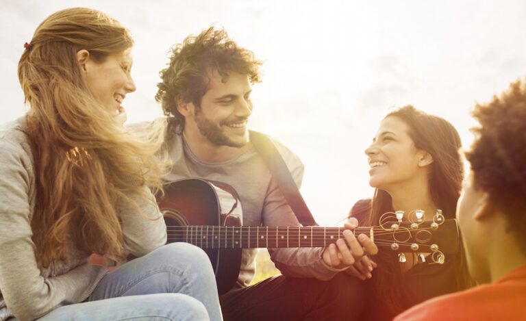 a man plays the guitar while a group sings a new song to God