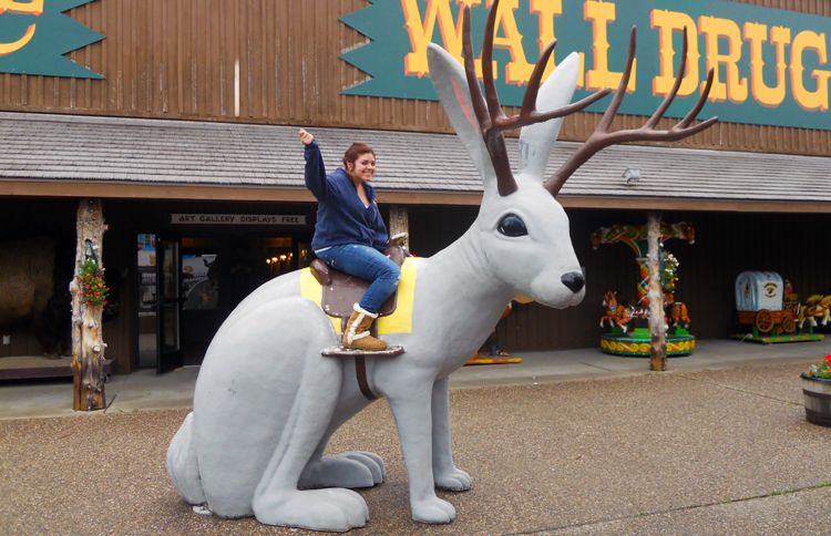 Guideposts: A tourist waves from her perch atop a giant jackalope at Wall Drug in Wall, South Dakota