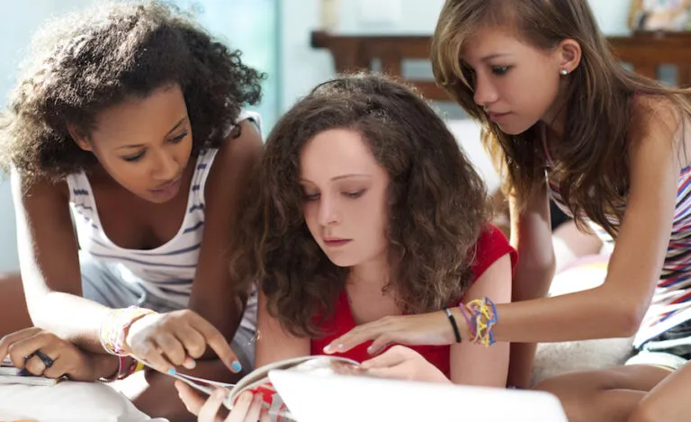 Teenage girls poring over fashion magazines.