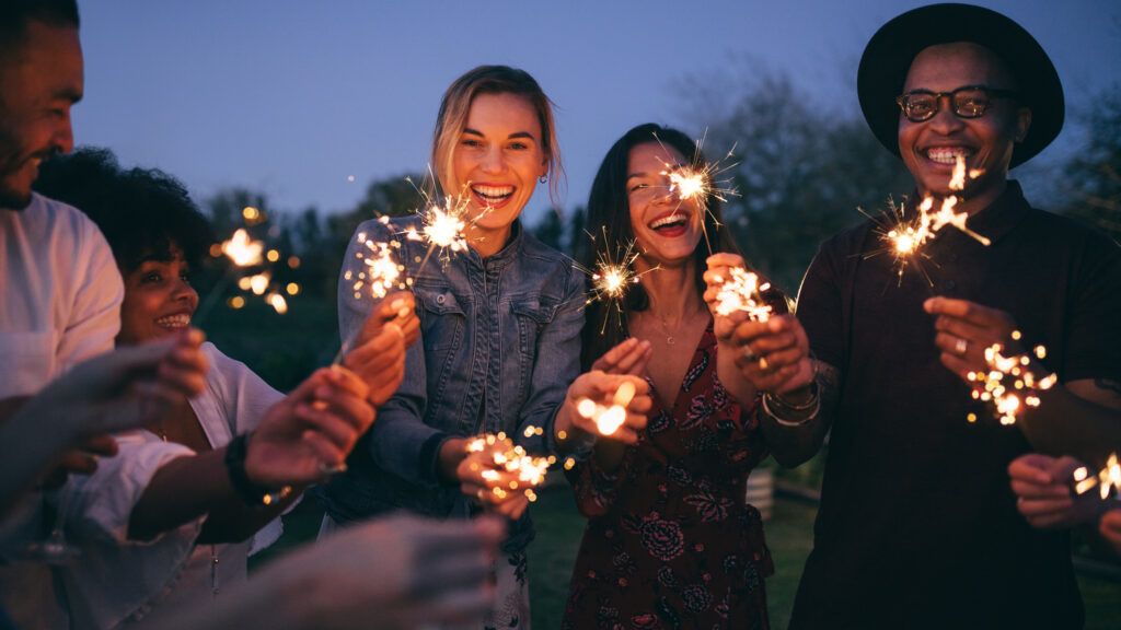 A group of friends with sparklers discussing how to prepare for new years