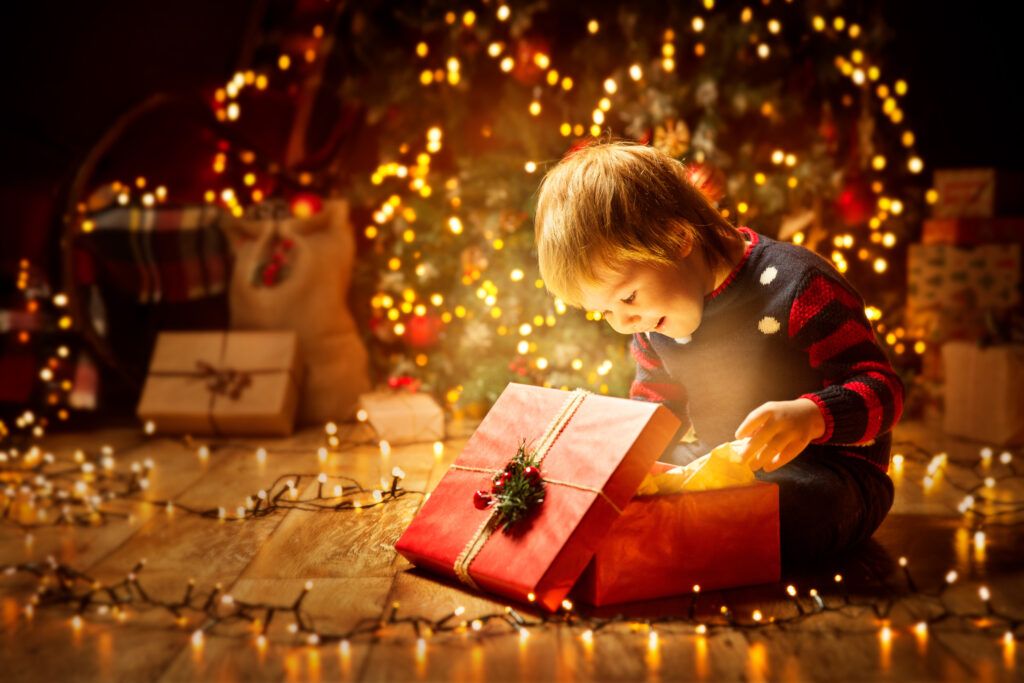 Happy child opens up a Christmas present surrounded by light
