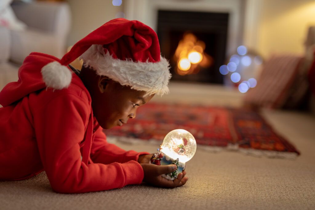 Boy staring into a snow globe with Christmas quotes