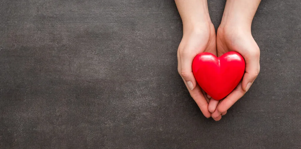 The woman is holding a red heart.