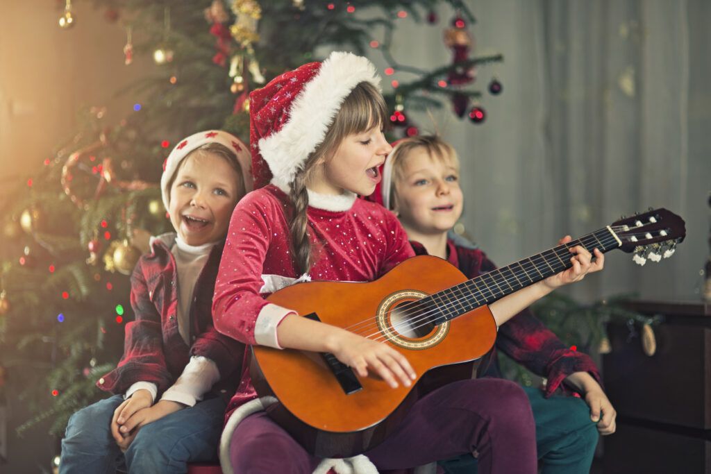 Kids singing carols and Christmas quotes near the christmas tree