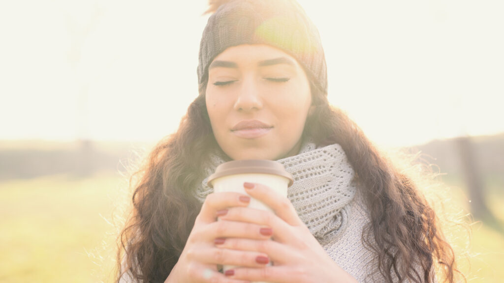 Woman in a scarf and hat with hot coffee saying a Christmas prayer