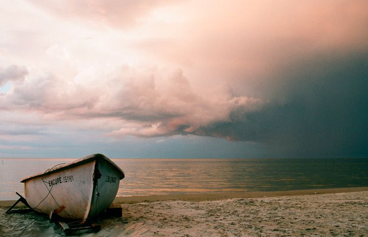 Boat sitting on the beach with a storm approaching with a new year bible verse