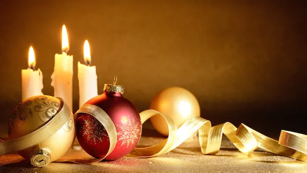 Lit candles and ornaments with ribbon being used in a Christmas prayer