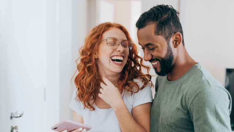 Couple laughing at funny Valentine's Day quotes on their phone