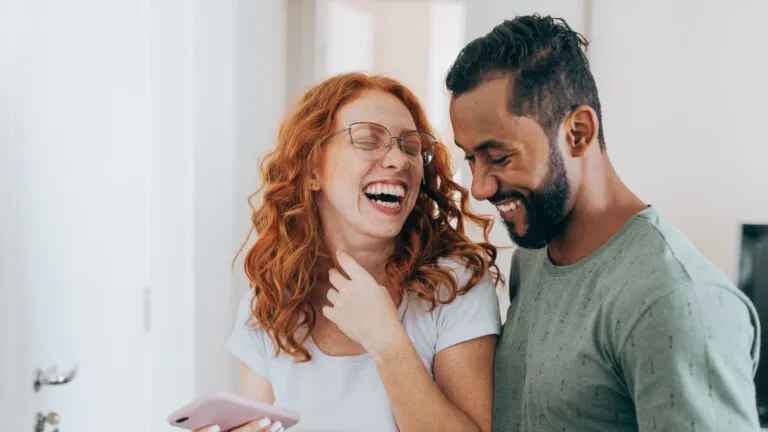 Couple laughing at funny Valentine's Day quotes on their phone