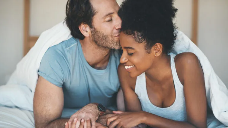 Couple lying in bed and kissing after reading romantic Valentine's Day quotes