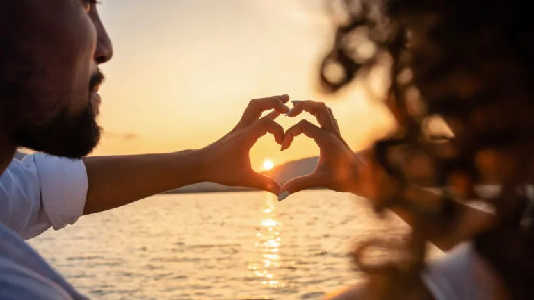 Couple making a heart with their hands at sunset after reading Valentine's day quotes about love