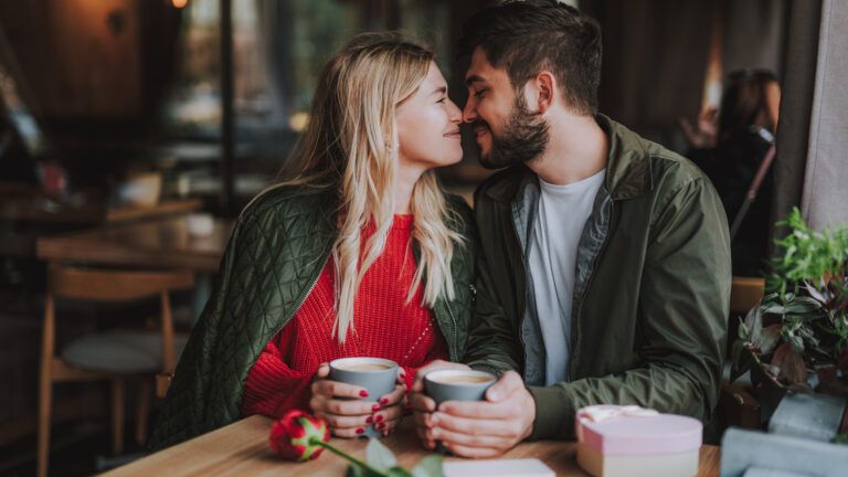 Couple touching noses at a coffee shop while reading Valentine's day quotes