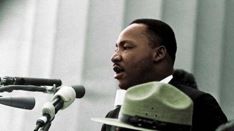 Dr. Martin Luther King Jr at a podium saying a prayer