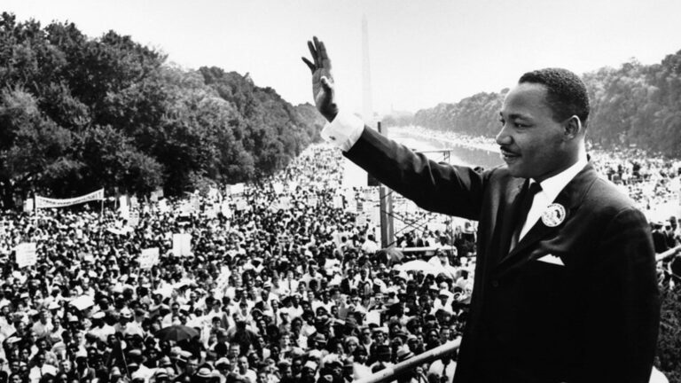 Dr. Martin Luther King Jr saying a prayer in front of a large crowd in Washington D.C.