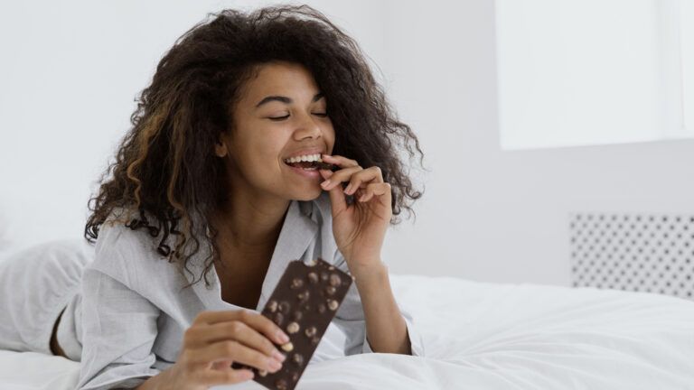 A woman eating chocolate in bed after learning if sundays count during lent