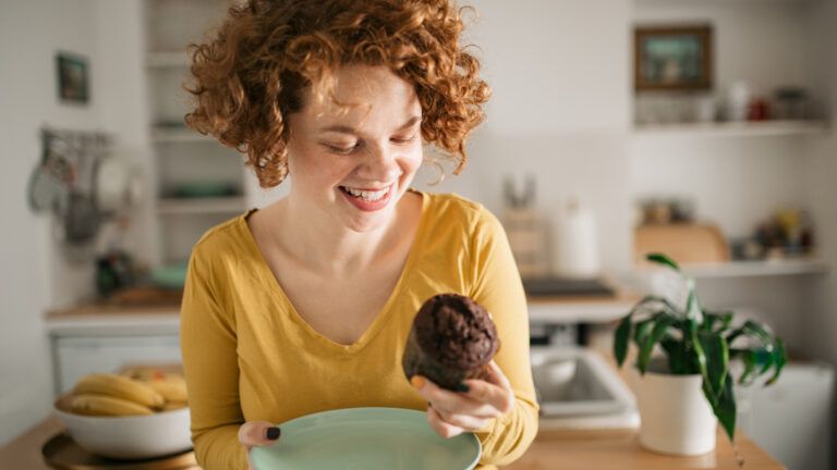 Woman looking at a chocolate muffin after learning that sundays don't count during Lent